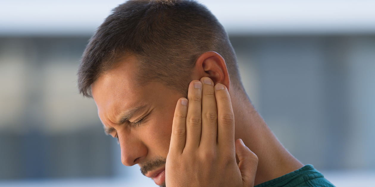 Man suffering from ear pain from hyperacusis.