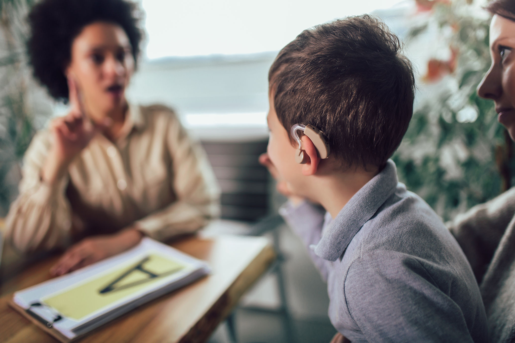 A child with hearing aid learning sign language. | ENT Family - Listening Beyond Ears: How to Talk to Someone with a Hearing Impairment