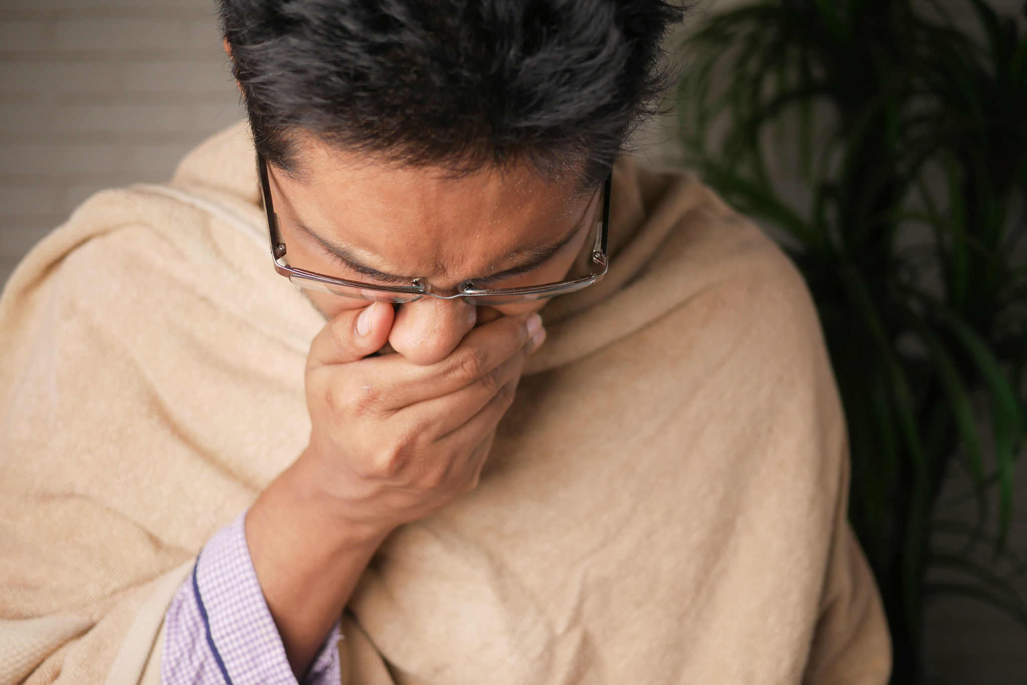 man covering his mouth and coughing
