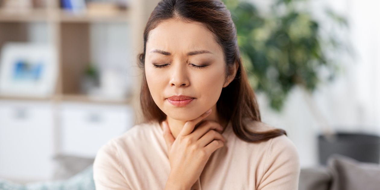 Woman appearing to have throat discomfort, tightness in throat.