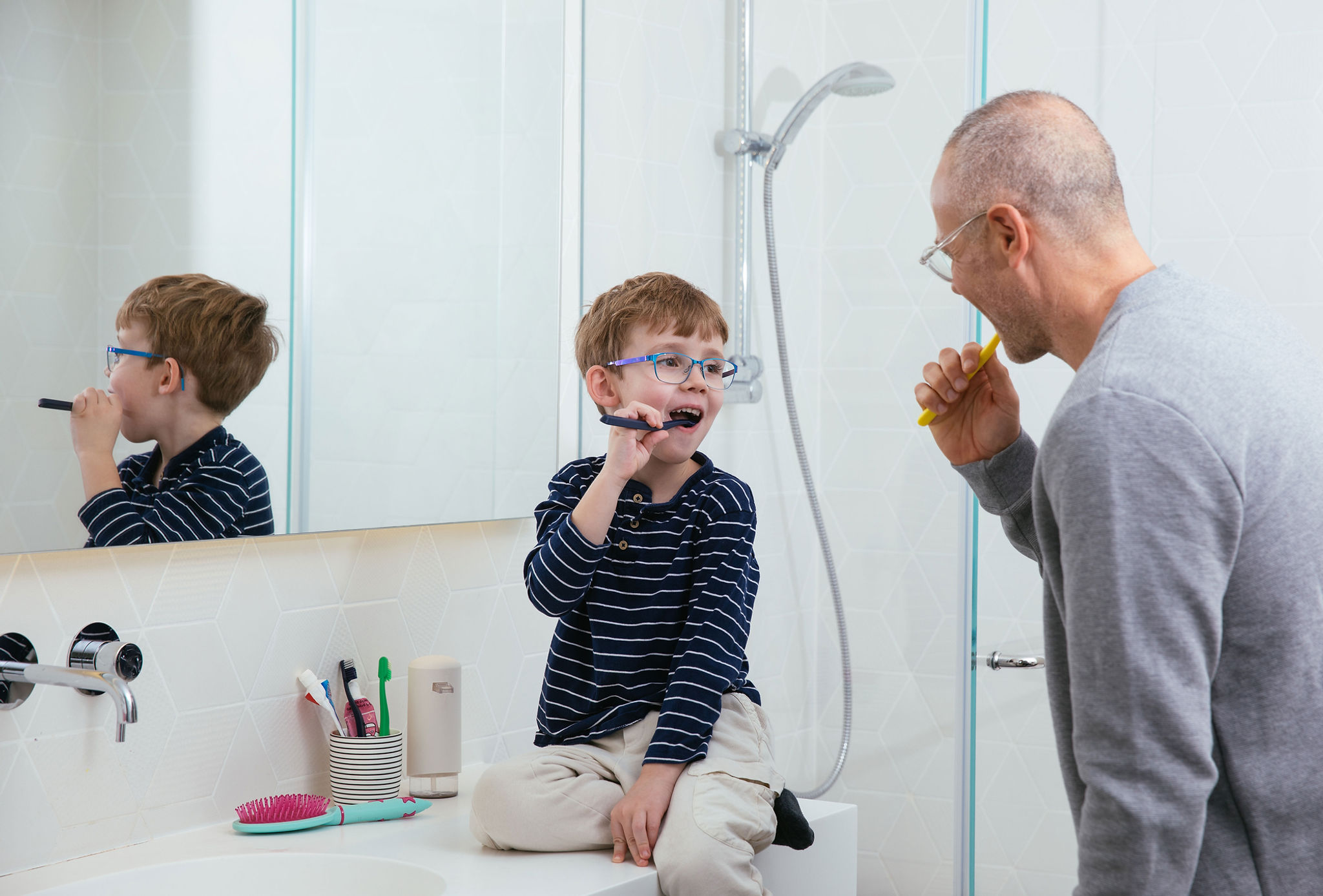 Father & son brushing teeth together. 