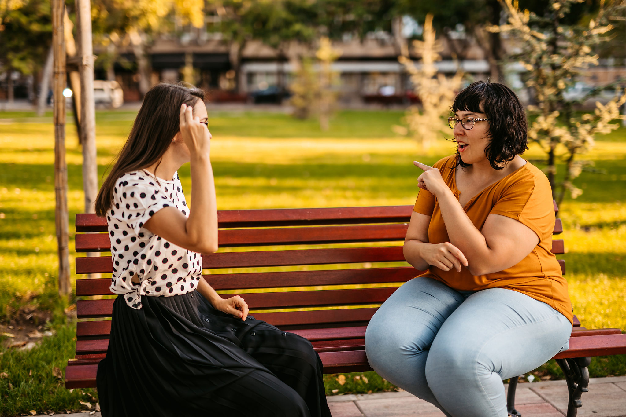 Women talking to each other with sign language on a park bench.  | ENT Family - Listening Beyond Ears: How to Talk to Someone with a Hearing Impairment